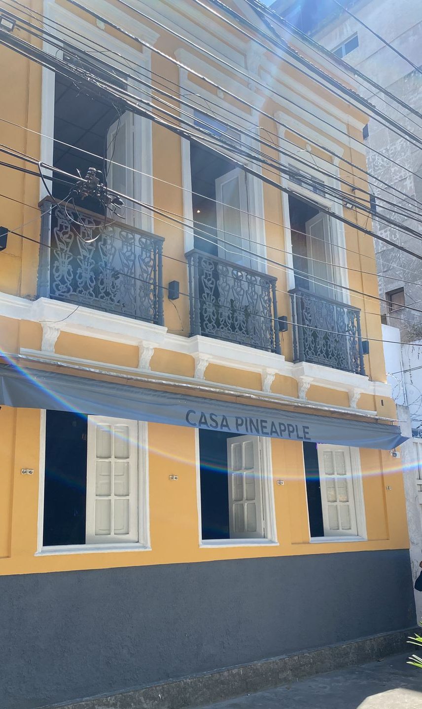 Fachada de um sobrado antigo amarelo, com janelas brancas e grade de ferro nas sacadas do segundo andar