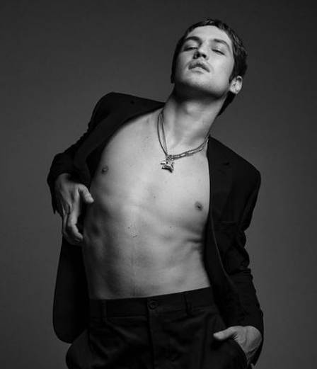 Gabriel Leone em foto preto e branco com calça, paletó e sem camisa