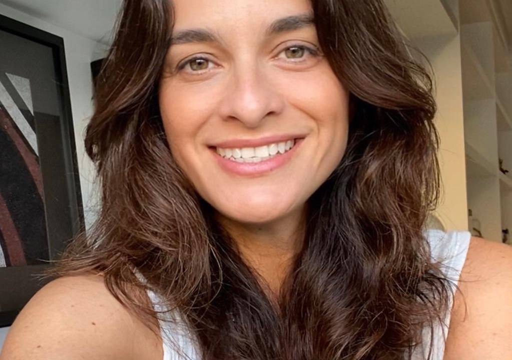 Foto de mulher branca, com cabelos castanhos longos e sorridente