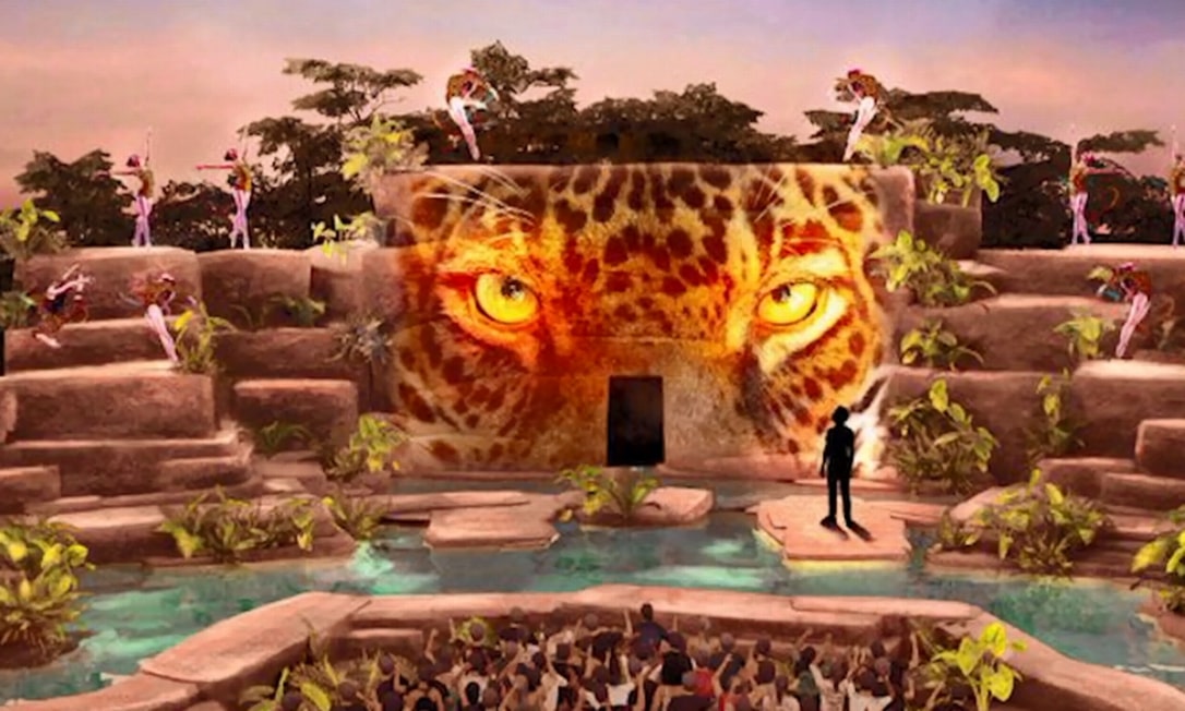 Ilustração de como será o cenário do espetáculo Uirapuru, com uma cachoeira artificial que sai de uma parede de blocos de pedra, o maior deles com a projeção de um rosto de uma onça. À direita, a silhueta de um ator.