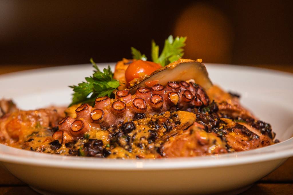 Moqueca negra: a sugestão da Casa Milà traz arroz negro com cubos de peixe, camarão e lascas de coco