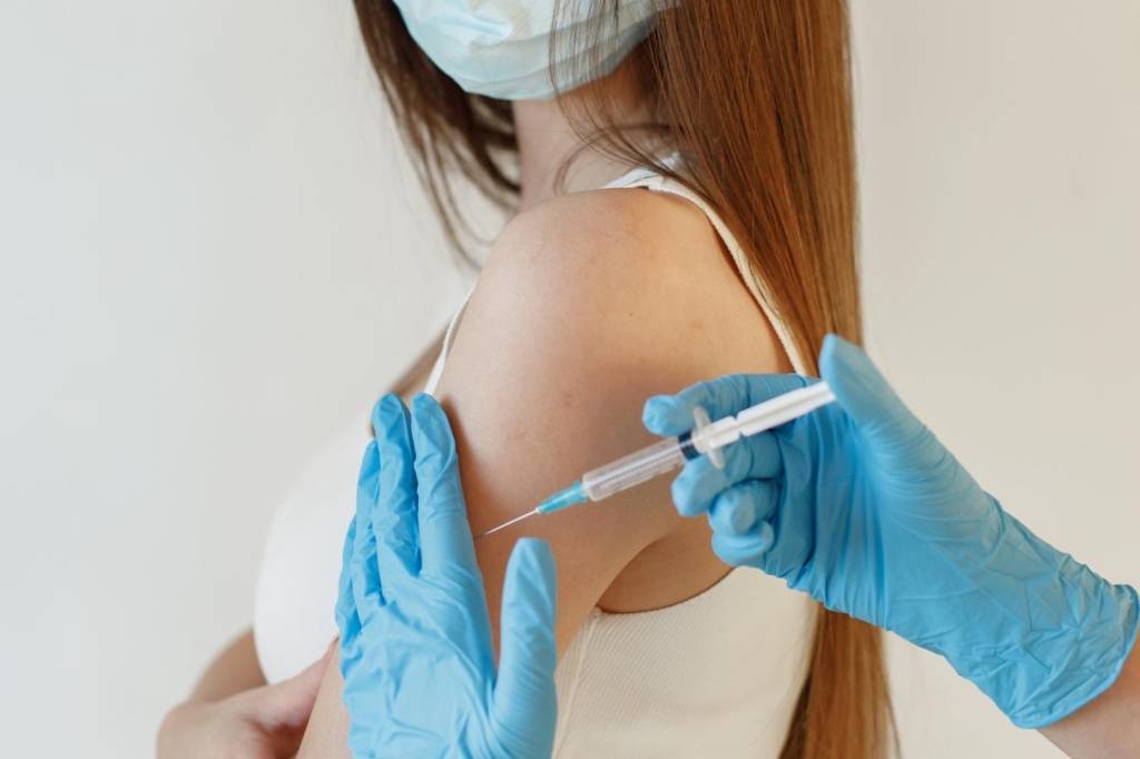 Foto mostra adolescente recebendo vacina
