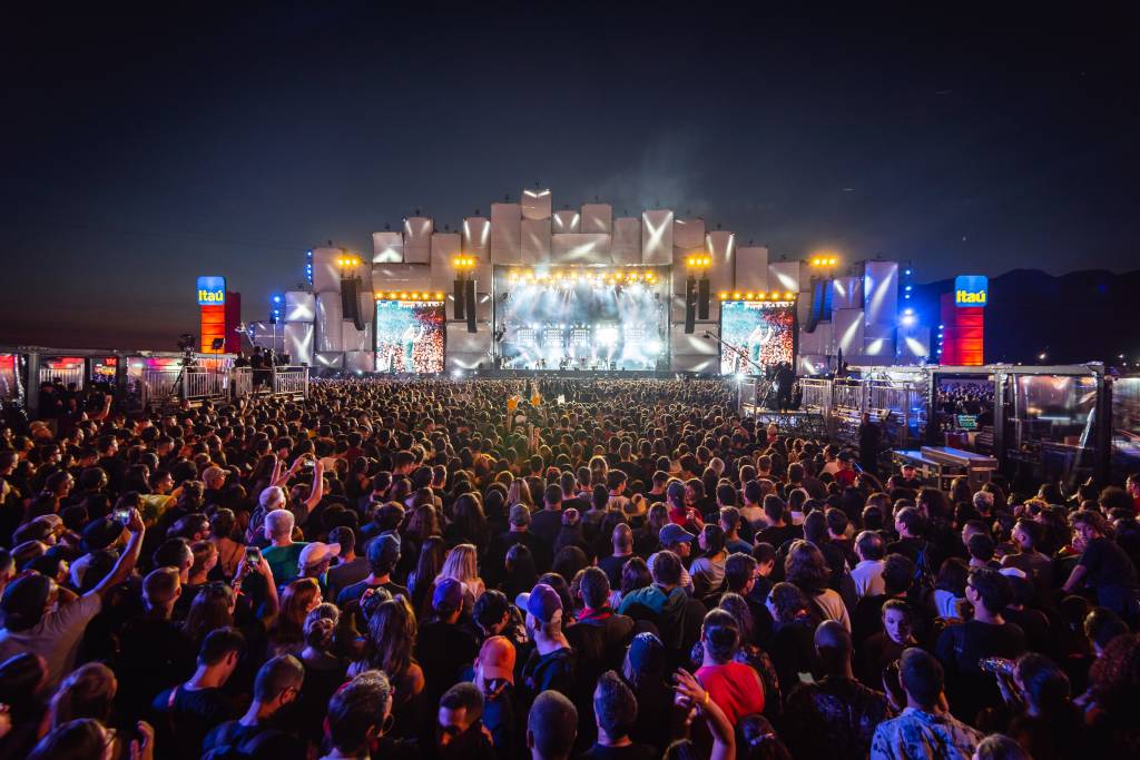 A multidão e, ao fundo, o palco Mundo, com as luzes acesas, durante show do Capital Inicial.