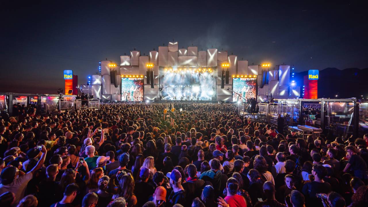 A multidão e, ao fundo, o palco Mundo, com as luzes acesas, durante show do Capital Inicial.