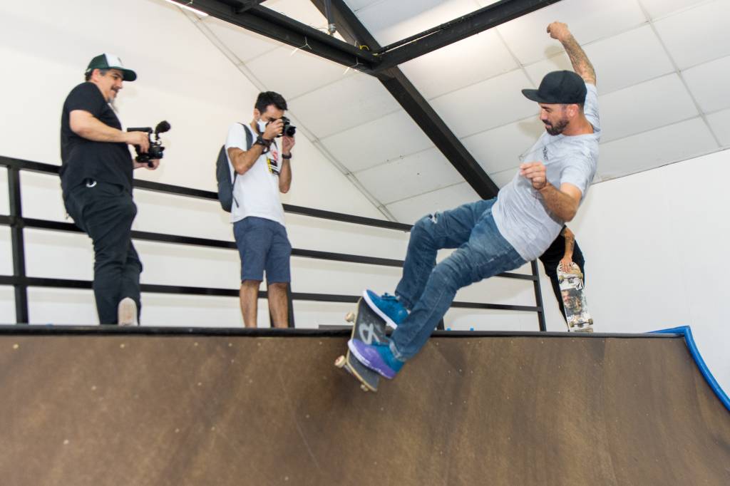 Bob Burnquist faz manobra no skate na pista enquanto é clicado por dois fotógrafos