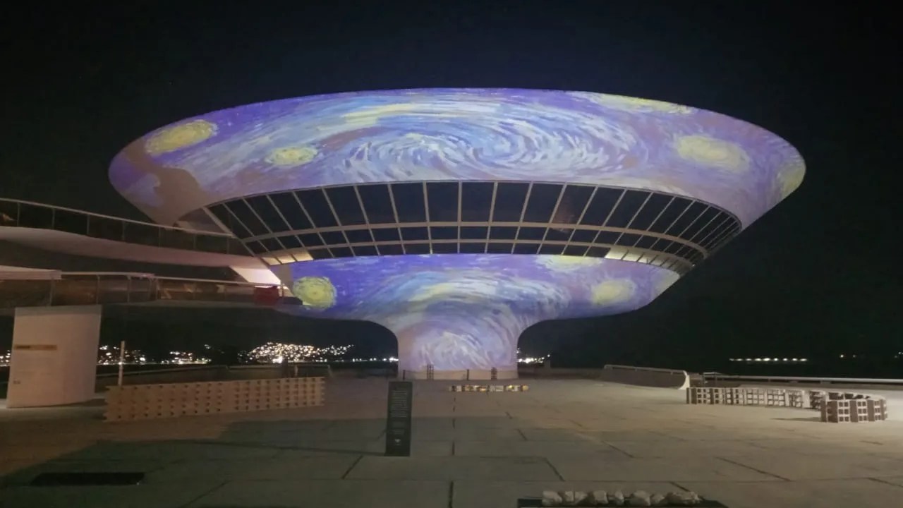 Foto mostra projeção da obra A Noite Estrelada de Van Gogh na fachada do Museu de Arte Contemporânea de Niterói, que possui formato de um disco voador