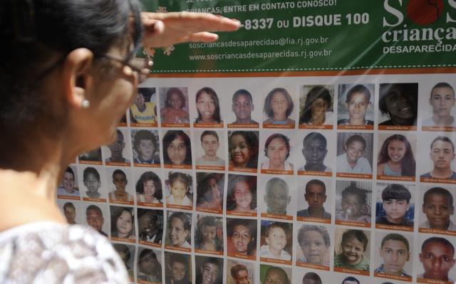 Mulher observa cartaz de desaparecidos no Rio