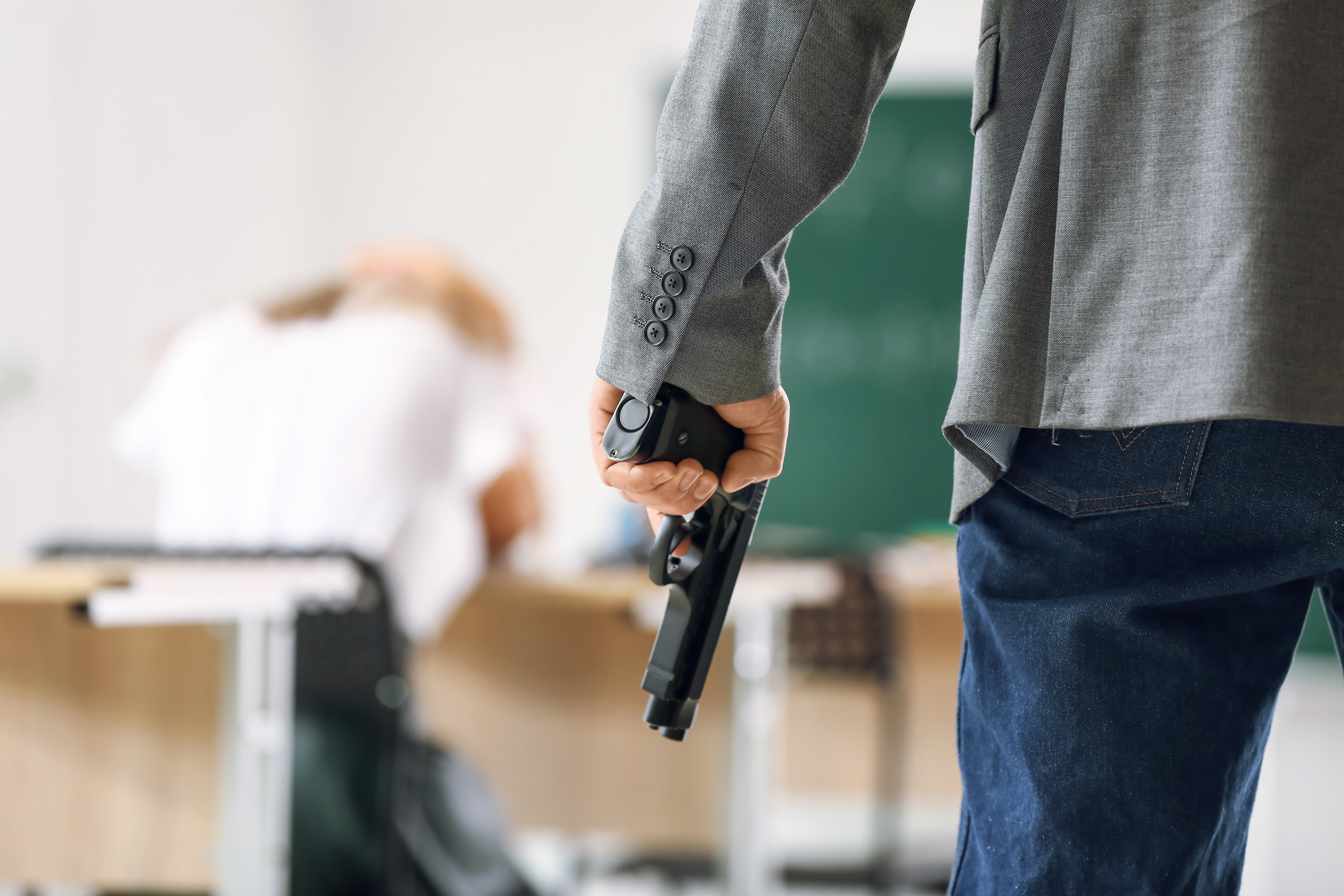Adolescente segura uma arma em uma sala de aula.