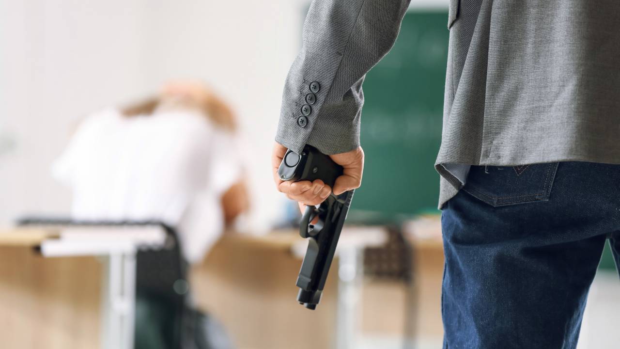Adolescente segura uma arma em uma sala de aula.