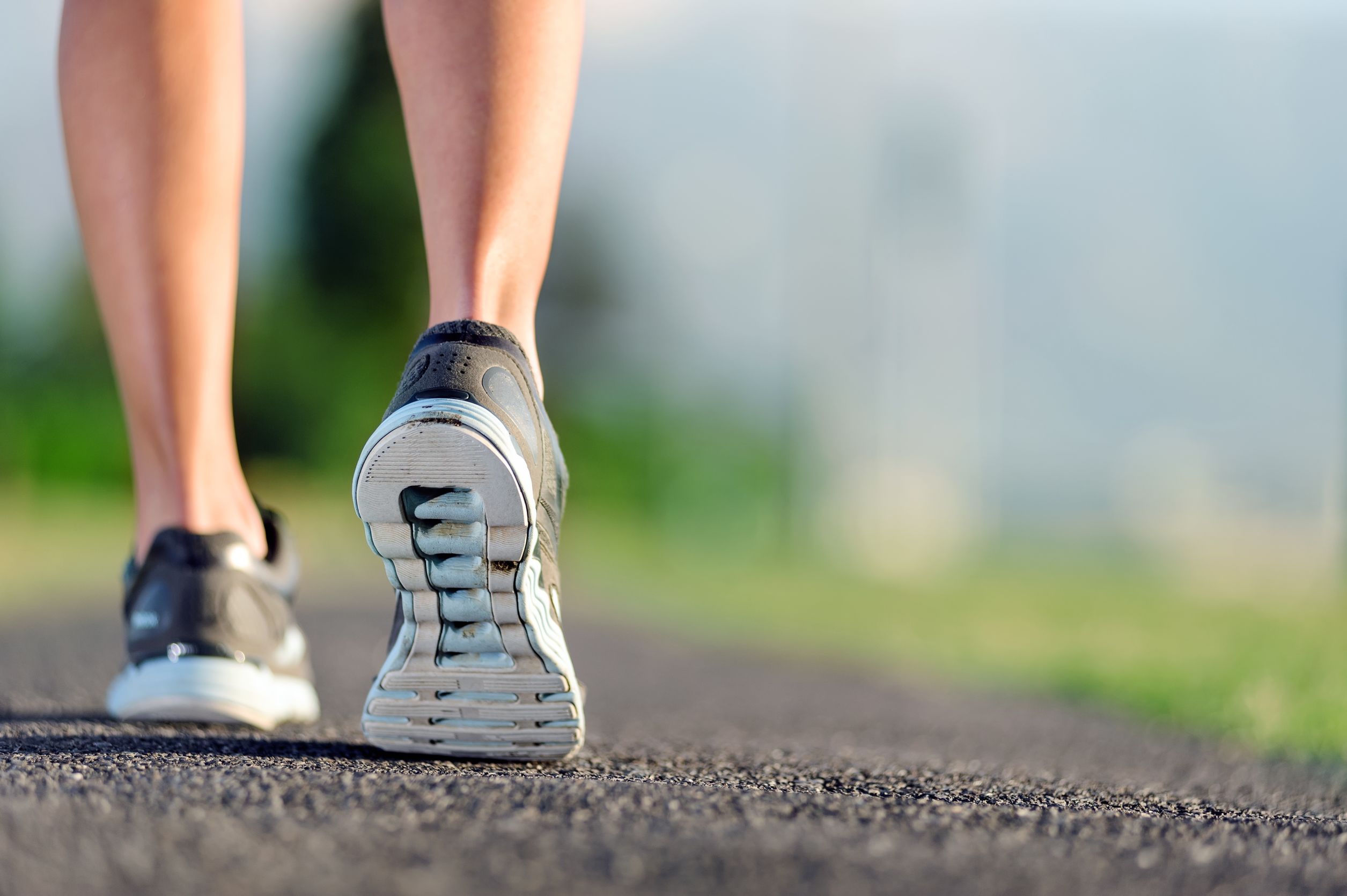 Pés calçados em tênis para correr no asfalto.