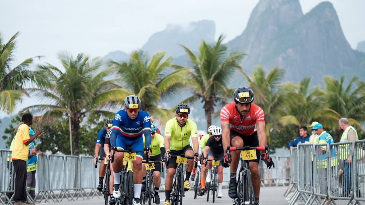 Foto mostra ciclistas em competição na orla de Ipanema