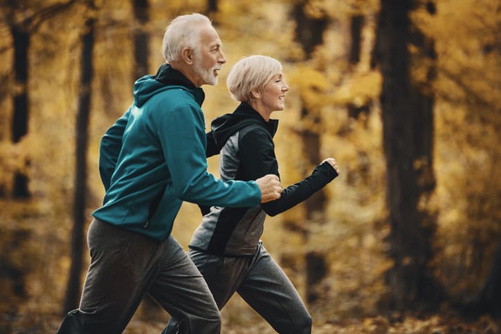 Homem e mulher de terceira idade correm fazendo exercícios.