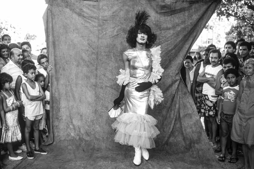 Folião fantasiado de mulher durante o carnaval de rua, em imagem em preto e branco.