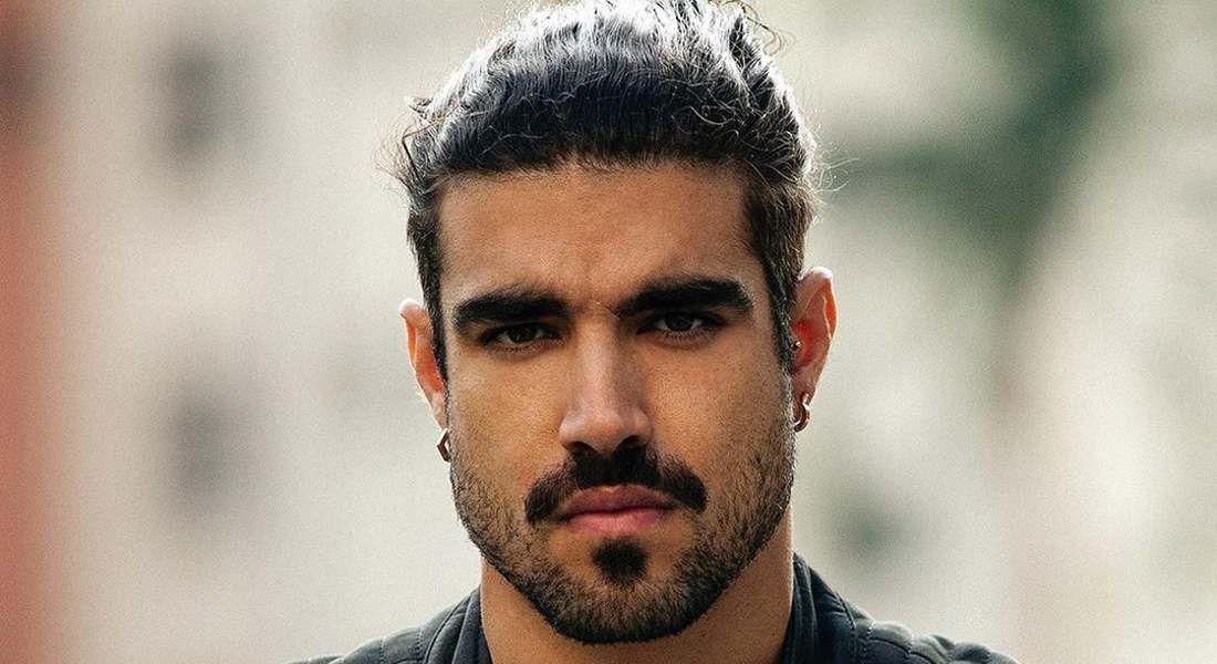Caio Castro de cabelo preso. Ele usa bigode, barba, cavanhaque e "mosca".