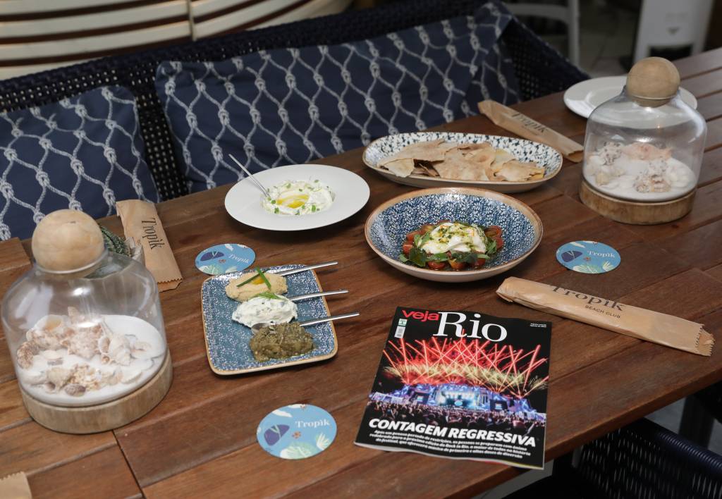 Foto mostra mesa do Tropik com comidas e uma revista