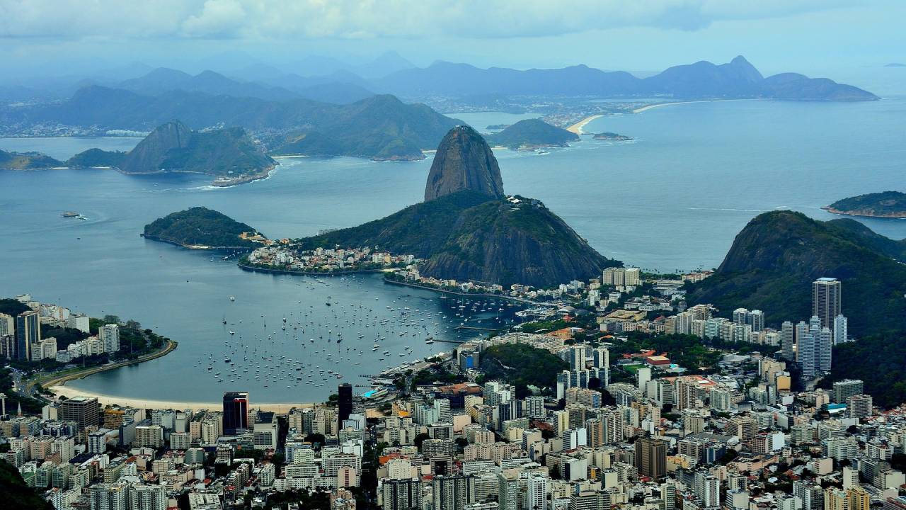 Foto mostra RIo de Janeiro do alto com vista para o Pão de Açúcar e o bairro de Botafogo