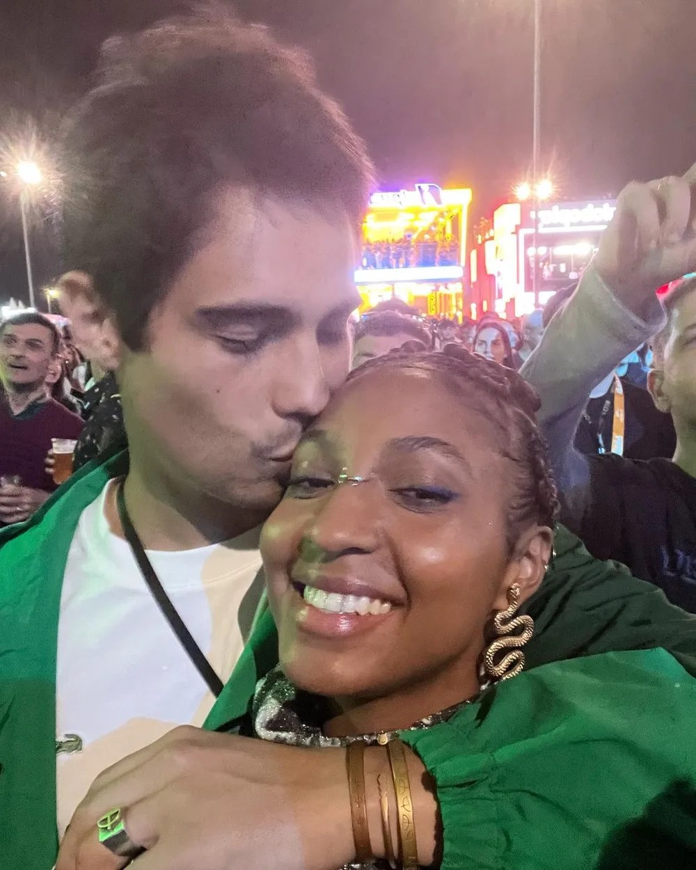 Foto de Domenica Dias e Danilo Mesquita abraçados durante um show no Rock in Rio. Ela sorri para a câmera e ele dá um beijo na testa dela