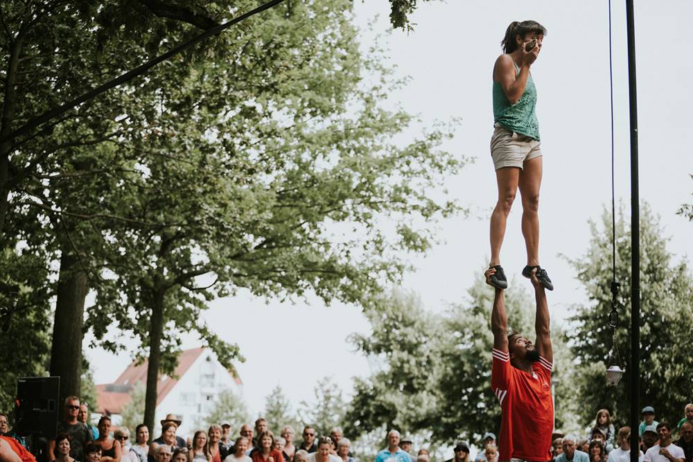 Uma mulher está de pé sobre as mãos de um homem em uma apresentação de acrobacia.