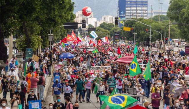 Passeata pela democracia com centenas de pessoas carregando faixas e bandeiras