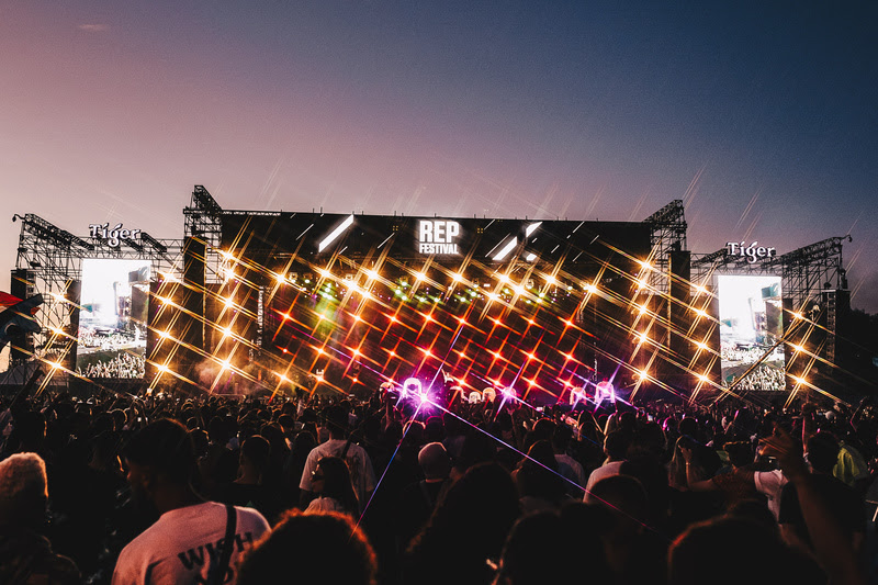 O palco do REP Festival com luzes e as o público fotografado de costas.