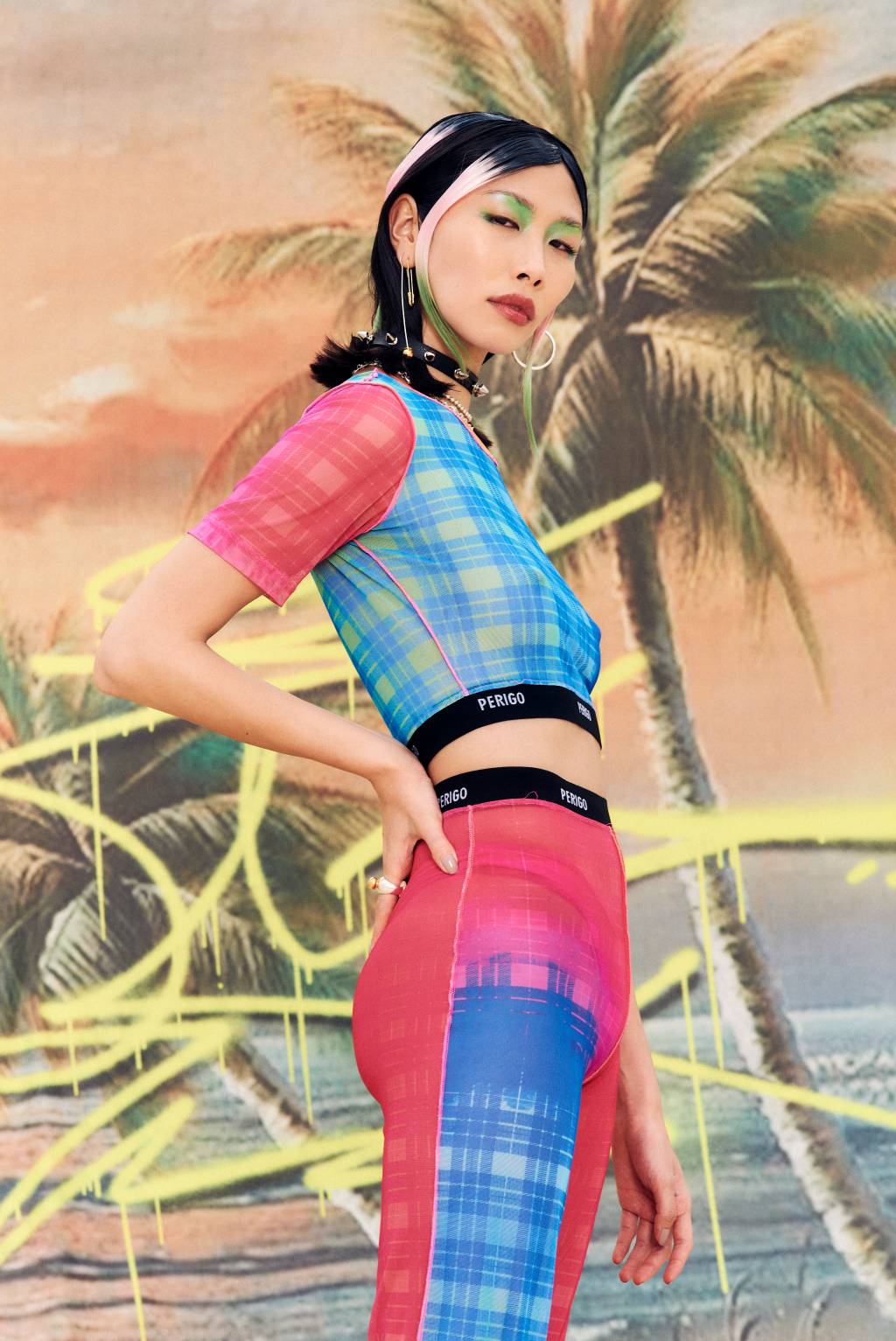 Foto mostra modelo usando blusa e calça coloridas com tecido transparente