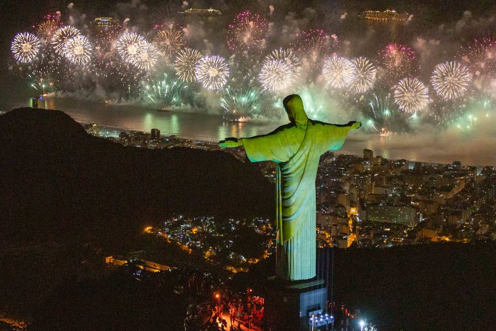 Os fogos de Copacabana vistos do alto, com o Cristo Redentor de costas iluminado por uma luz verde