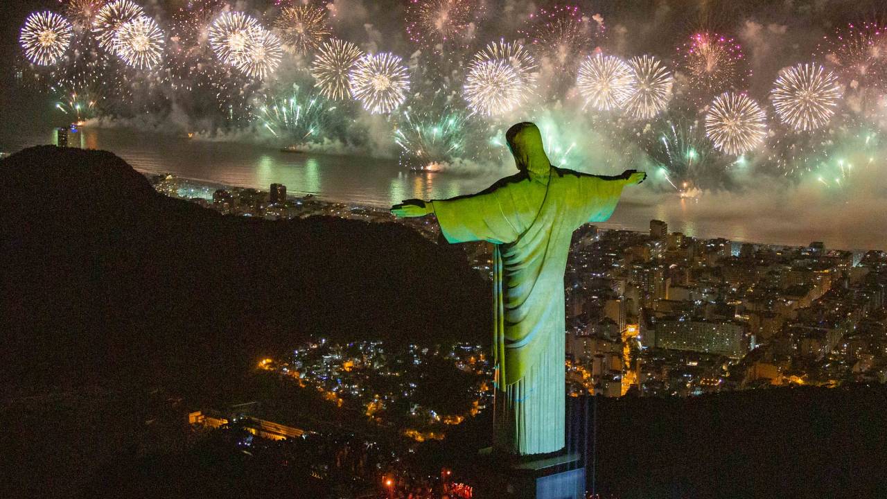 Os fogos de Copacabana vistos do alto, com o Cristo Redentor de costas iluminado por uma luz verde