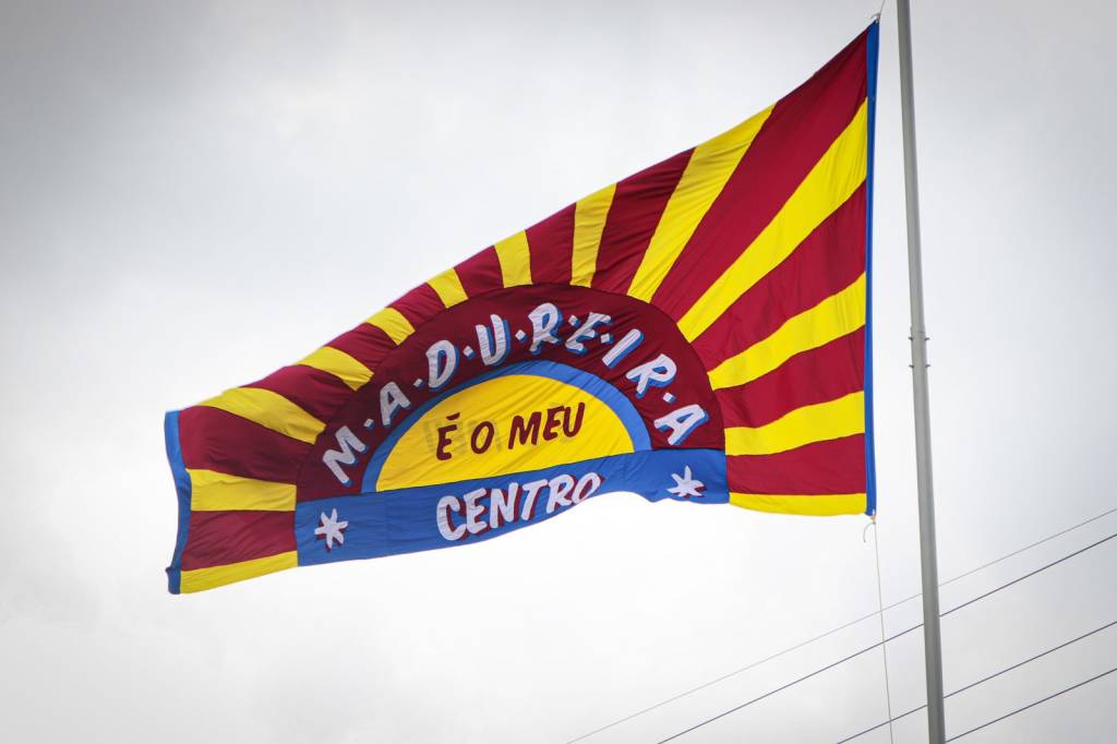 Foto mostra bandeira vermelha, amarela e azul com os dizeres "Madureira ´o meu centro"