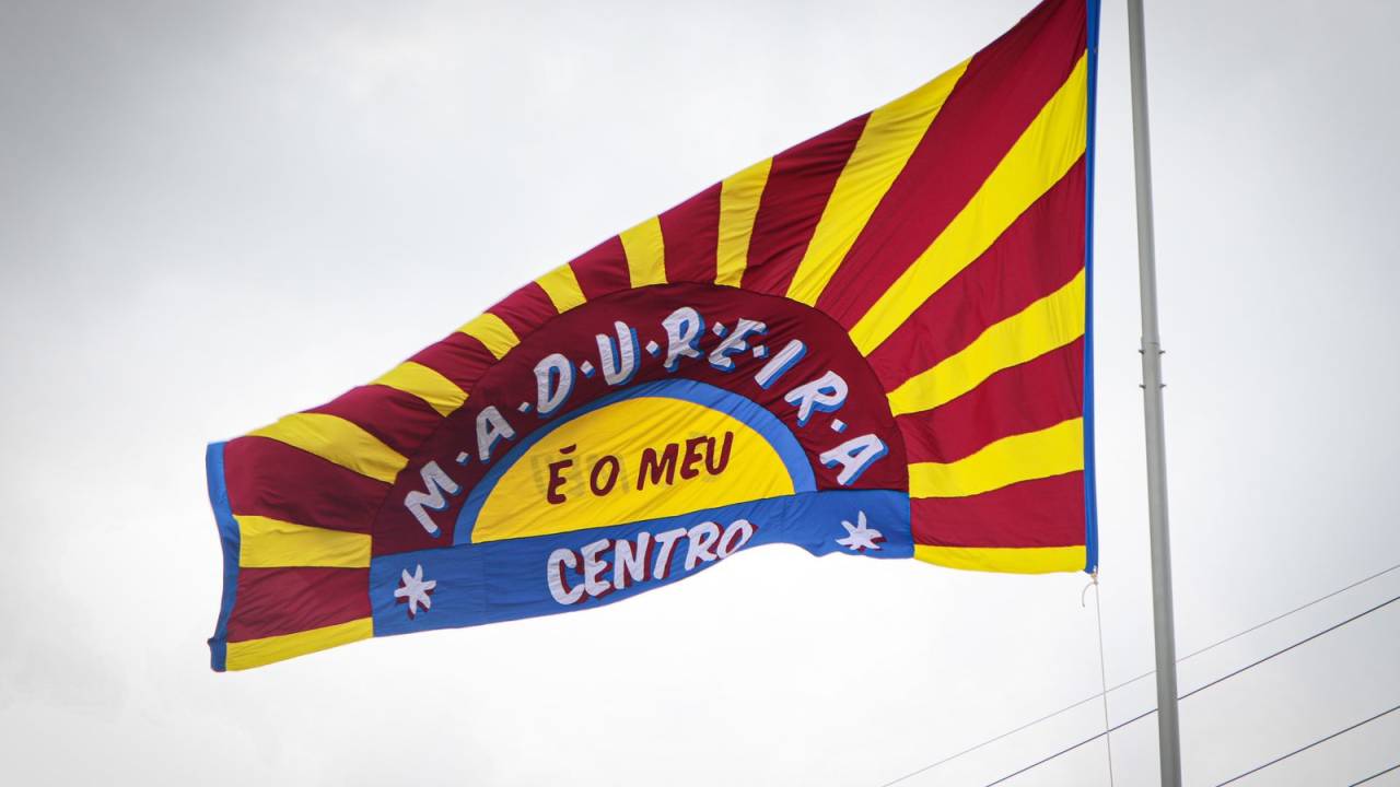 Foto mostra bandeira vermelha, amarela e azul com os dizeres "Madureira ´o meu centro"