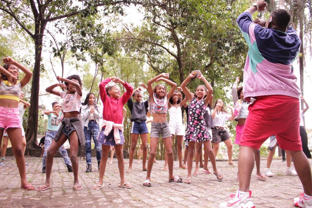 Foto mostra grupo de crianças dançando, imitando instrutor