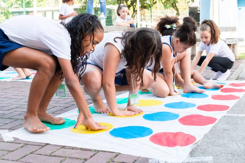 Foto mostra crianças brincando em tapete com bolas coloridas