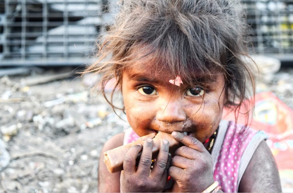 Foto mostra menina pequena e suja comendo algo