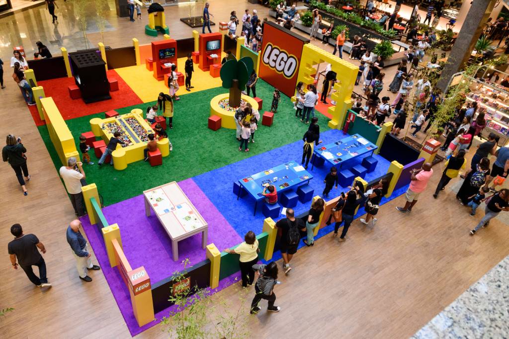 Foto mostra crianças brincando em espaço colorido com a temática Lego