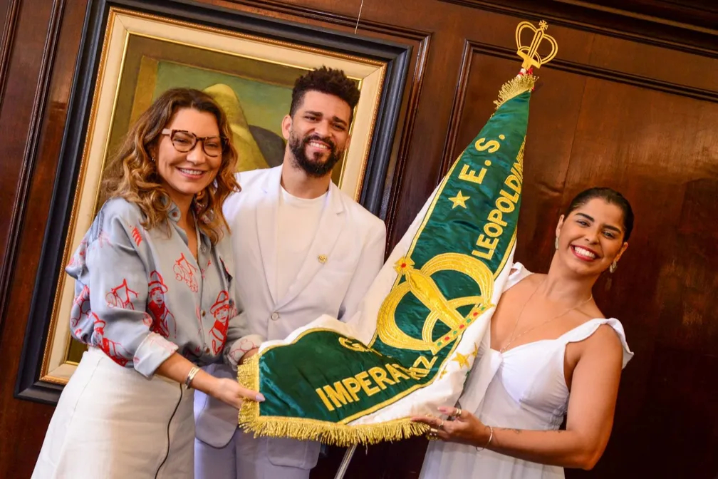 A primeira-dama Janja Lula da Silva, o mestre-sala Phelipe Lemos e a porta-bandeira Rafaela Theodoro, da Imperatriz Leopoldinense, seguram o pavilhão da escola.