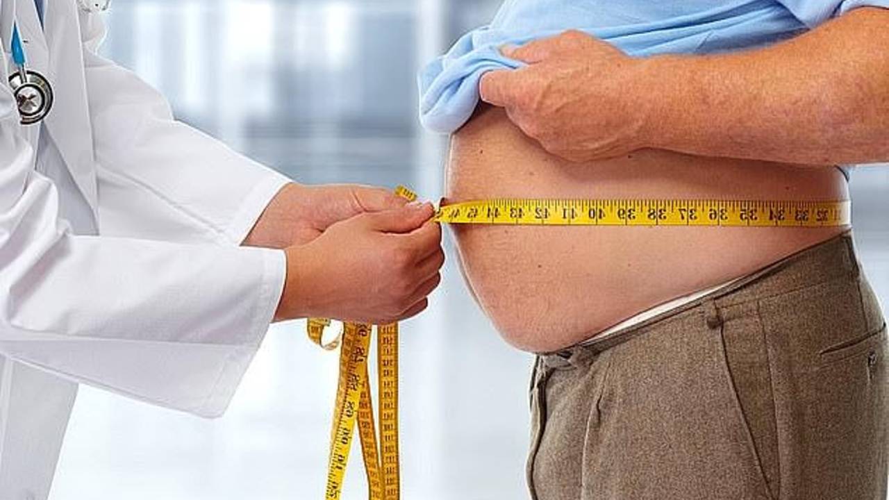 Médico mede a circunferência de homem obeso.