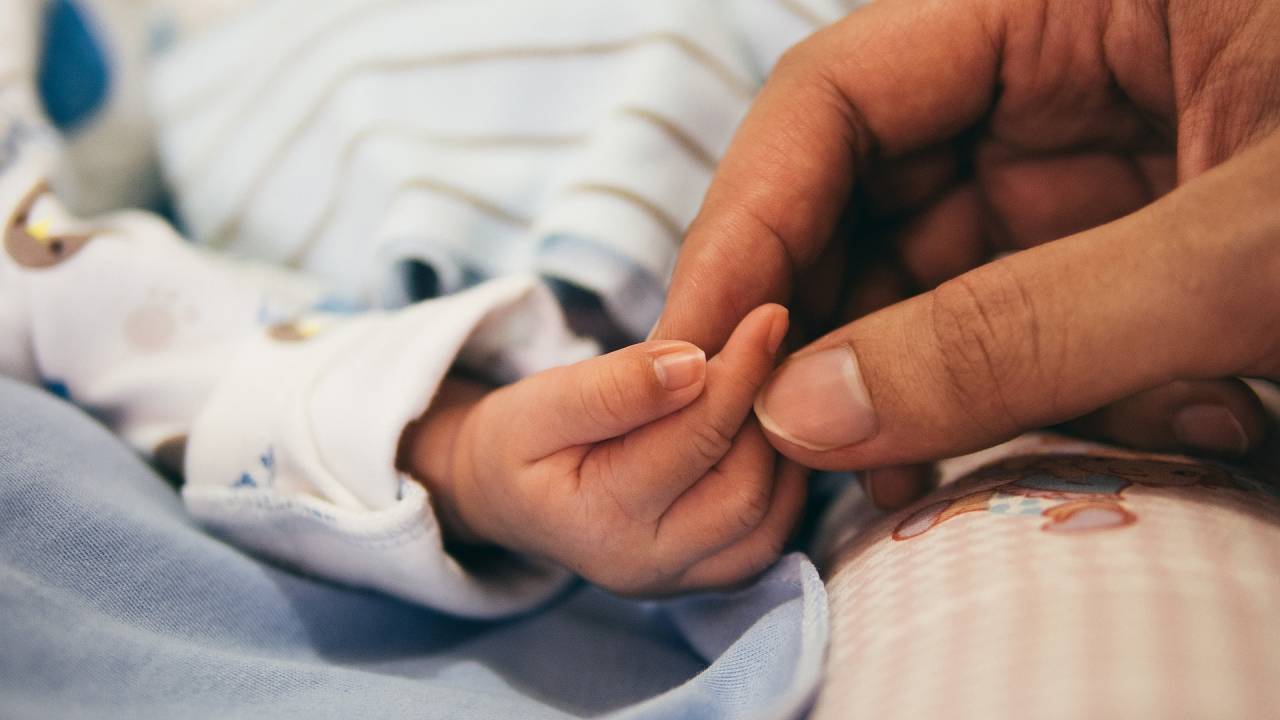 Foto mostra mão de recém-nascido tocando dedo de humano