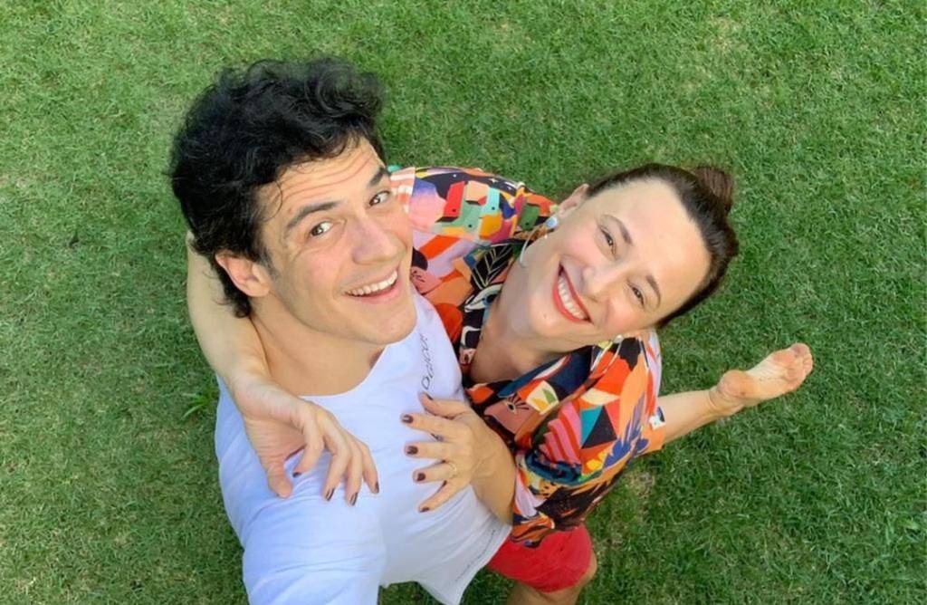 Mateus Solano e Paula Braun em pé, sobre a grama, abraçados e fotografados de cima