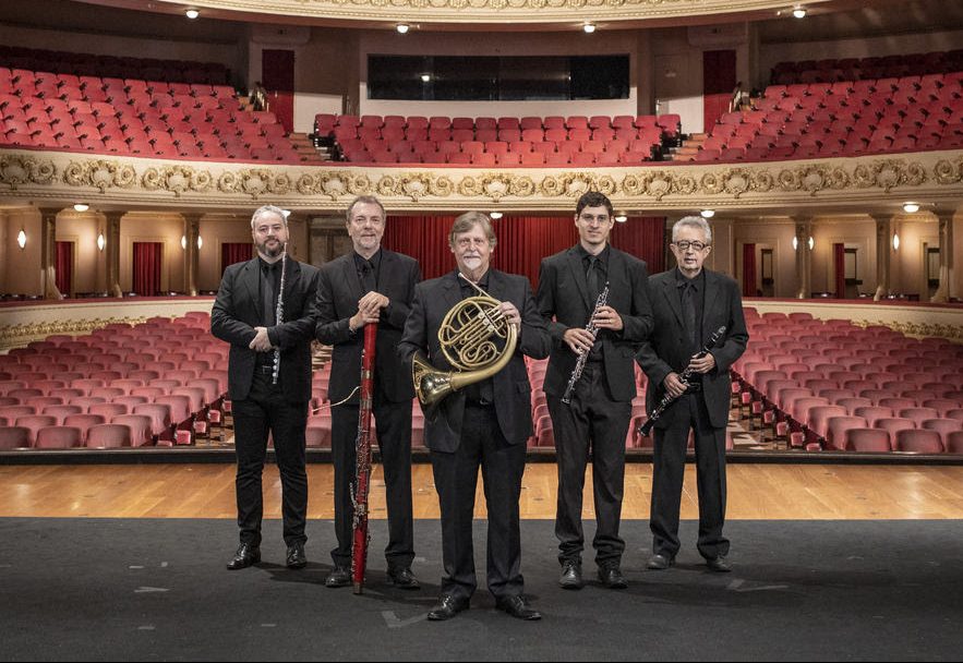 Os músicos do Quinteto Villa-Lobos, no palco, vestidos de preto e segurando seus respectivos instrumentos.