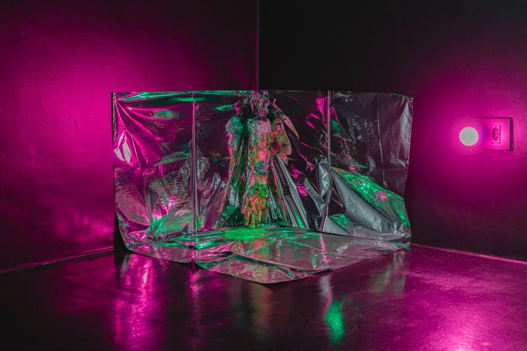 Foto da uma escultura em forma de um polígono quadrilátero tridimensional vazado furta-cor