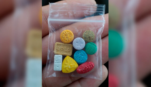 Comprimidos coloridos de drogas sintéticas em um saquinho plástico.
