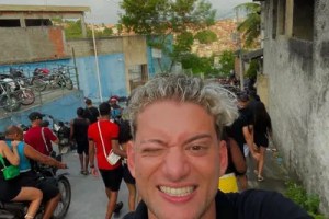 Foto mostra youtuber com cabelo pintado de loiro fazendo selfie em favela carioca