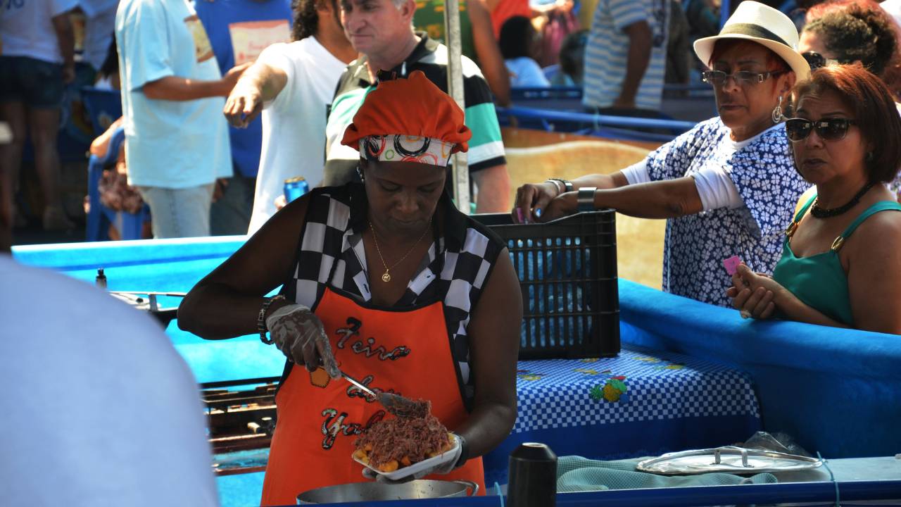 Foto mostra tia servindo comida na feira das yabás