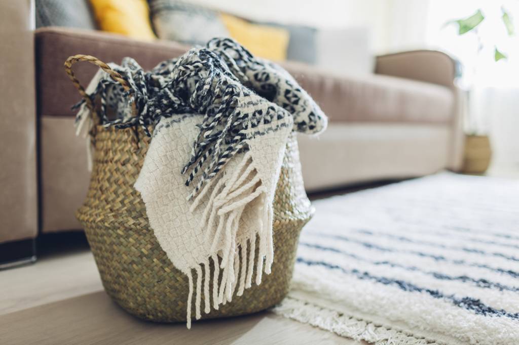 GettyImages-1149347775.jpg Traga lenços, xales e pashminas esquecidos no fundo do armário para um cesto de palha perto da sala de TV.