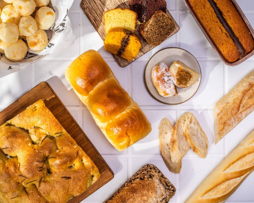 Mesa com vários tipos de pão e bolos fotografada de cima