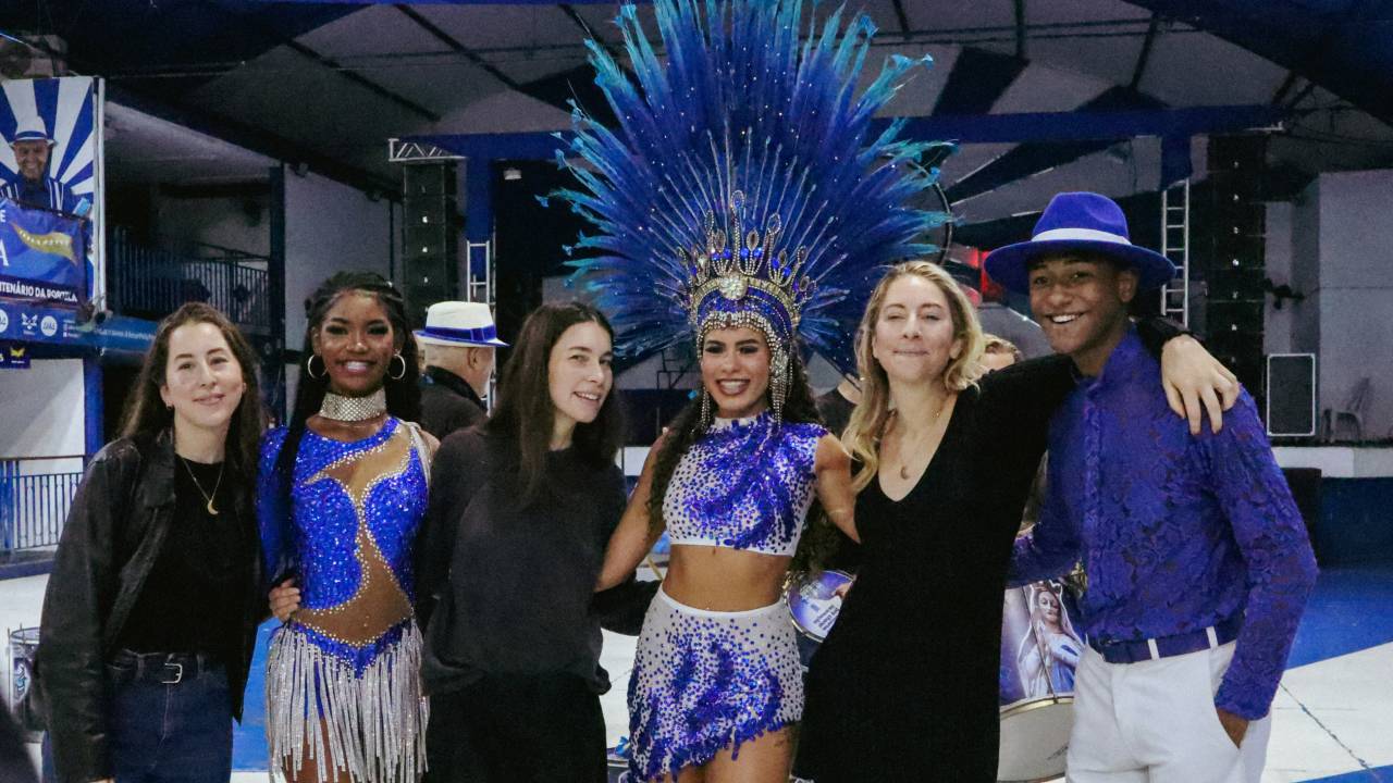 Foto mostra irmãs HAIM abraçadas com passistas da Portela