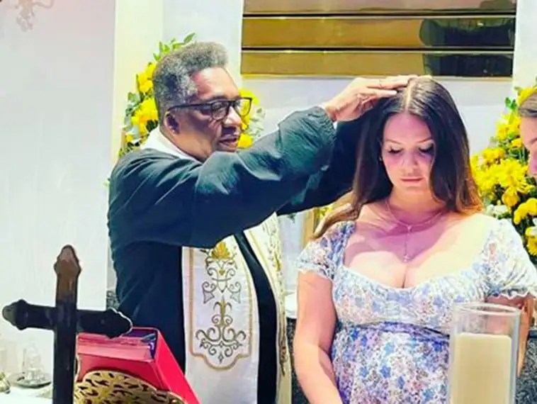 Foto mostra a cantora Lana del Rey sendo abençoada por padre dentro de igreja