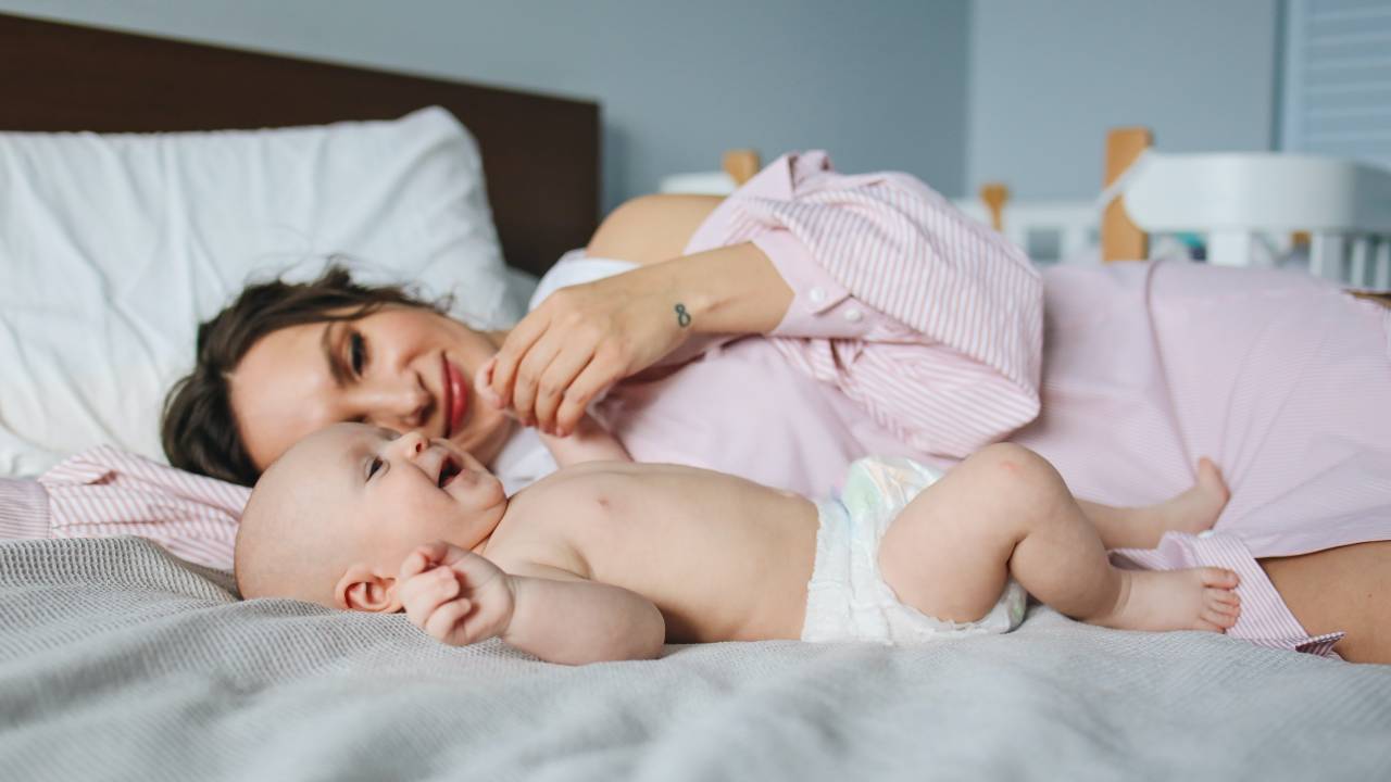 Um bebê e sua mãe deitados na cama