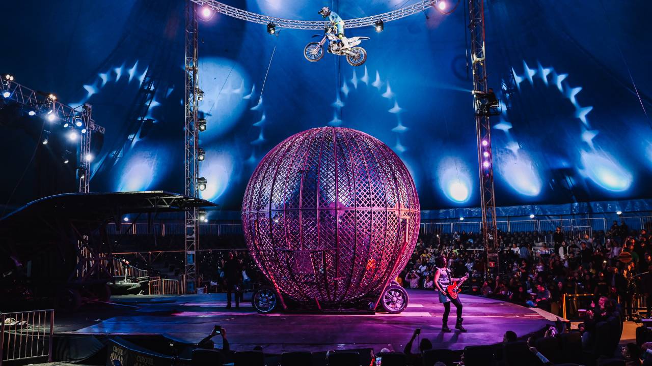 Foto mostra o globo da morte do Cirque Amar com uma moto passando por cima