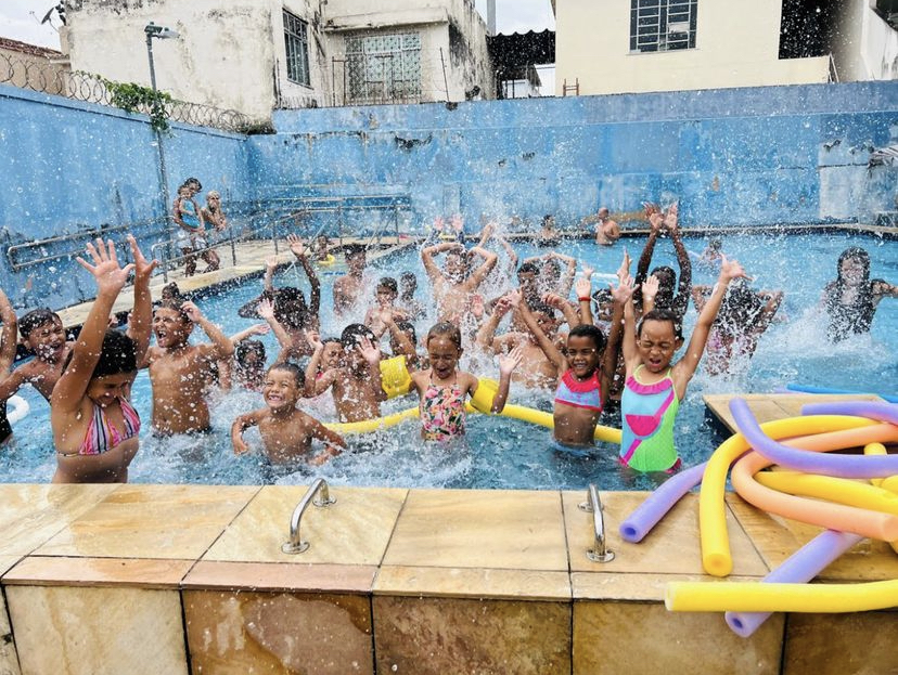 Foto mostra crianças tomando banho de piscina