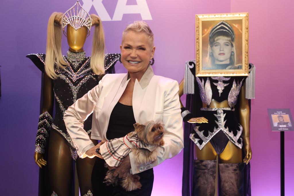 Foto mostra Xuxa posando com cachorrinha na frente de looks icônicos usados por ela